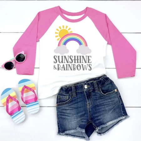 Pink and white baseball style shirt with image of the sun and a rainbow and saying Sunshine and Rainbows