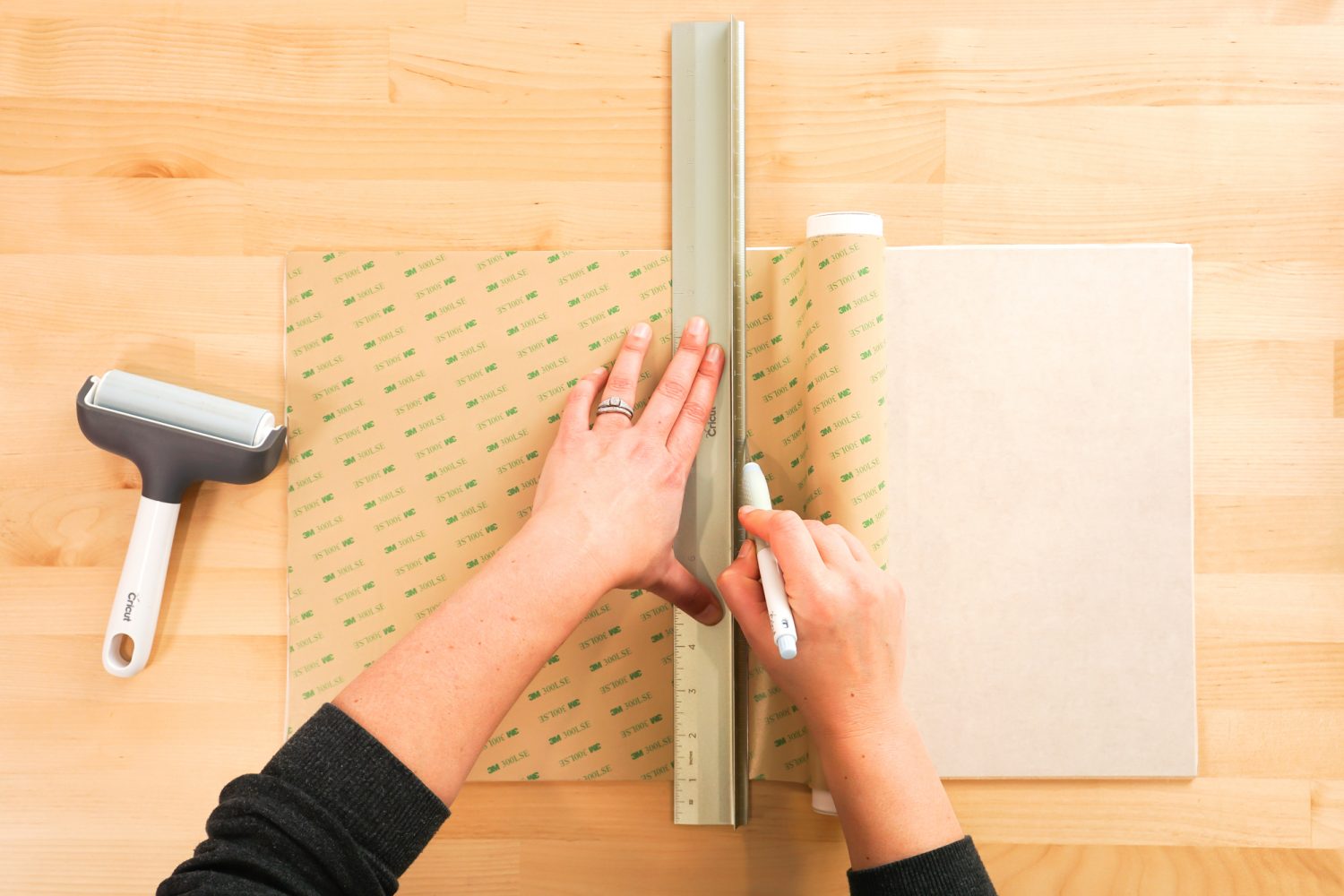 hands using a craft knife to cut the adhesive