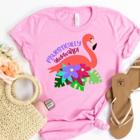 A pink t-shirt with an image of a pink flamingo surrounded by flowers and the saying Majestically Awkward