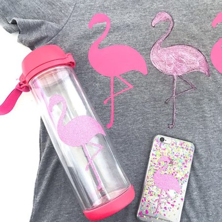 A pink flamingo on a water tumbler and one of a cell phone case and three flamingo's on a t-shirt