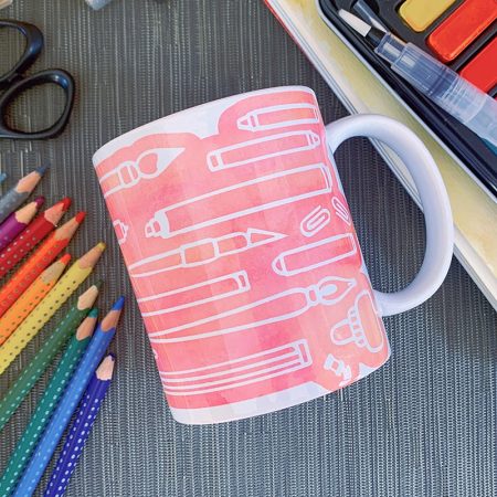 White mug decorated with images of pink art supplies