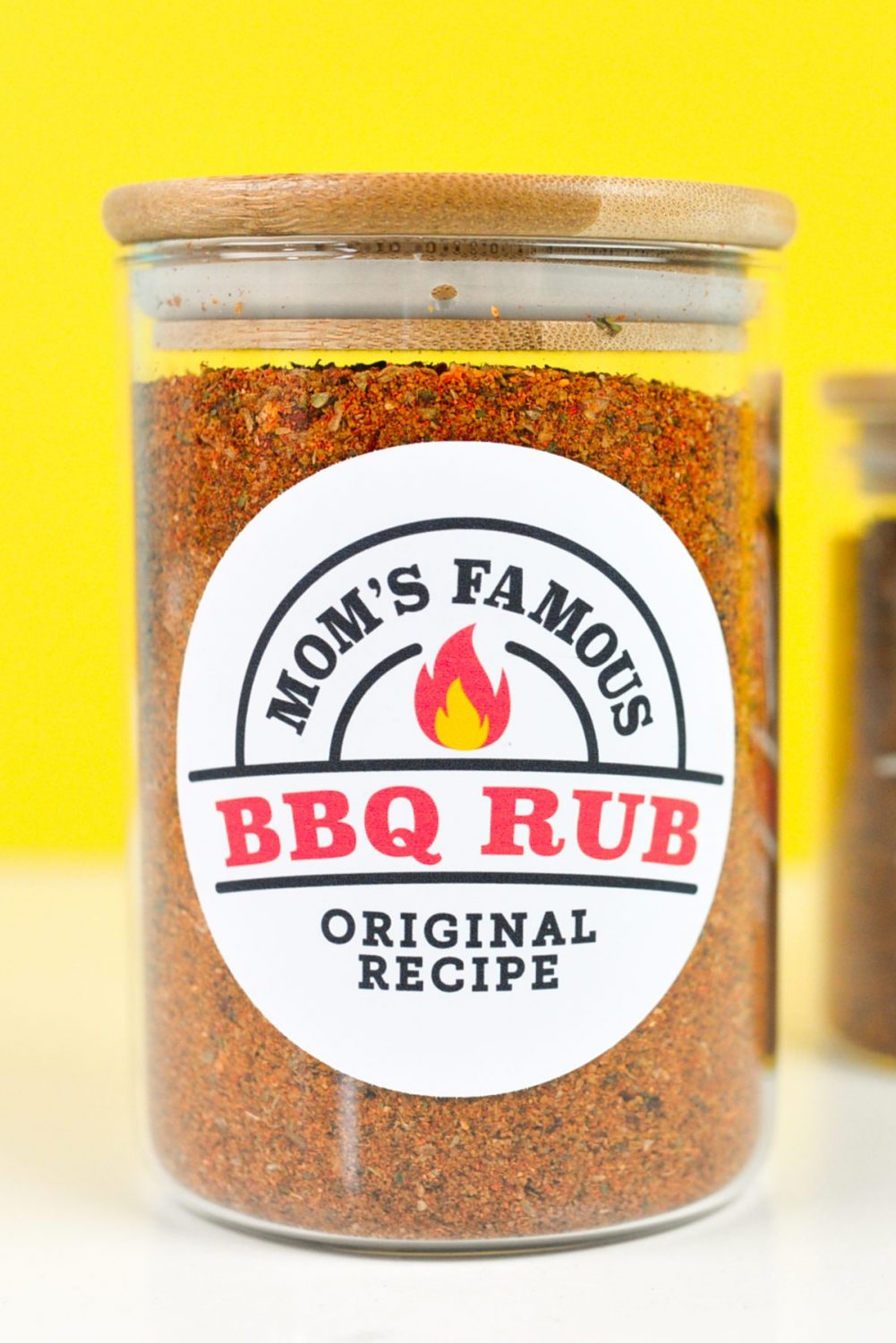 Close up of labeled BBQ rub jar in front of a yellow background
