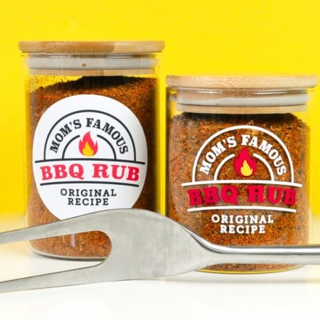 Two jars with two BBQ labels in front of a yellow background with barbecue utensil