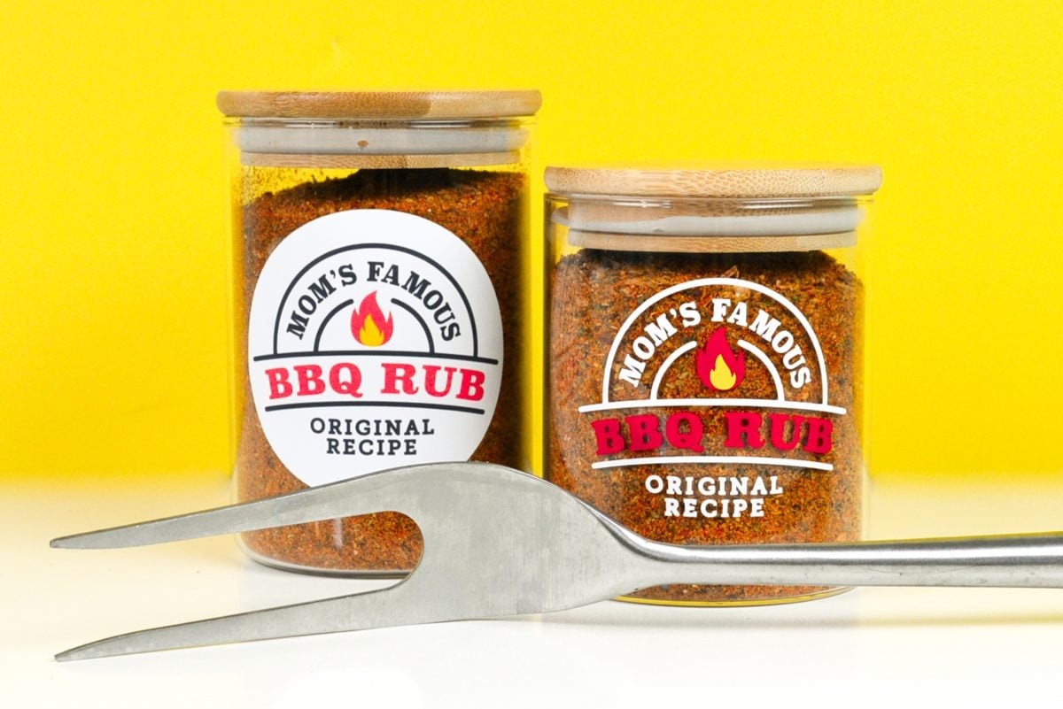 Two jars with two BBQ labels in front of a yellow background with barbecue utensil