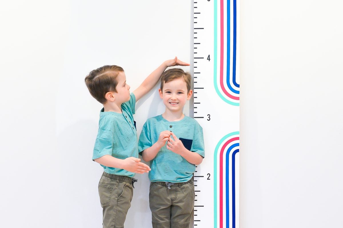 Twin boys standing with height ruler