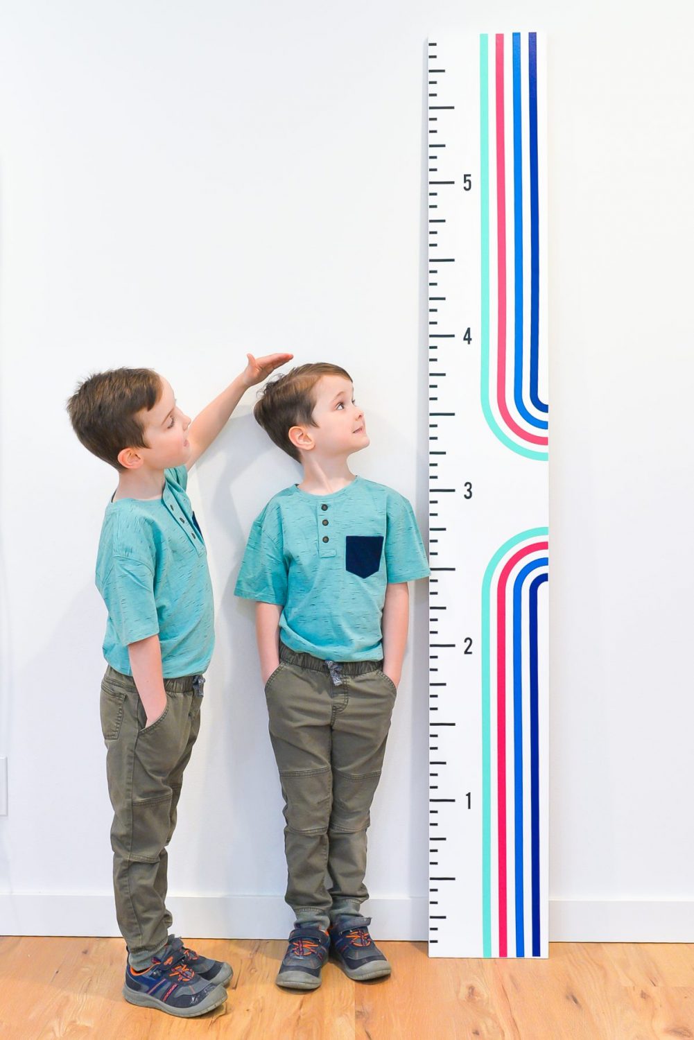 Twin boys standing with height ruler