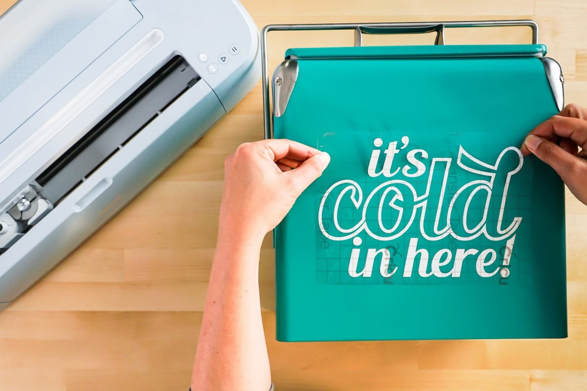 Hands placing decal on ice chest.