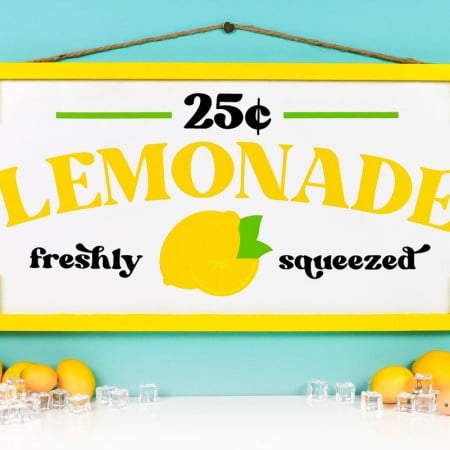 Finished lemonade stand sign on teal background styled with faux lemons and ice