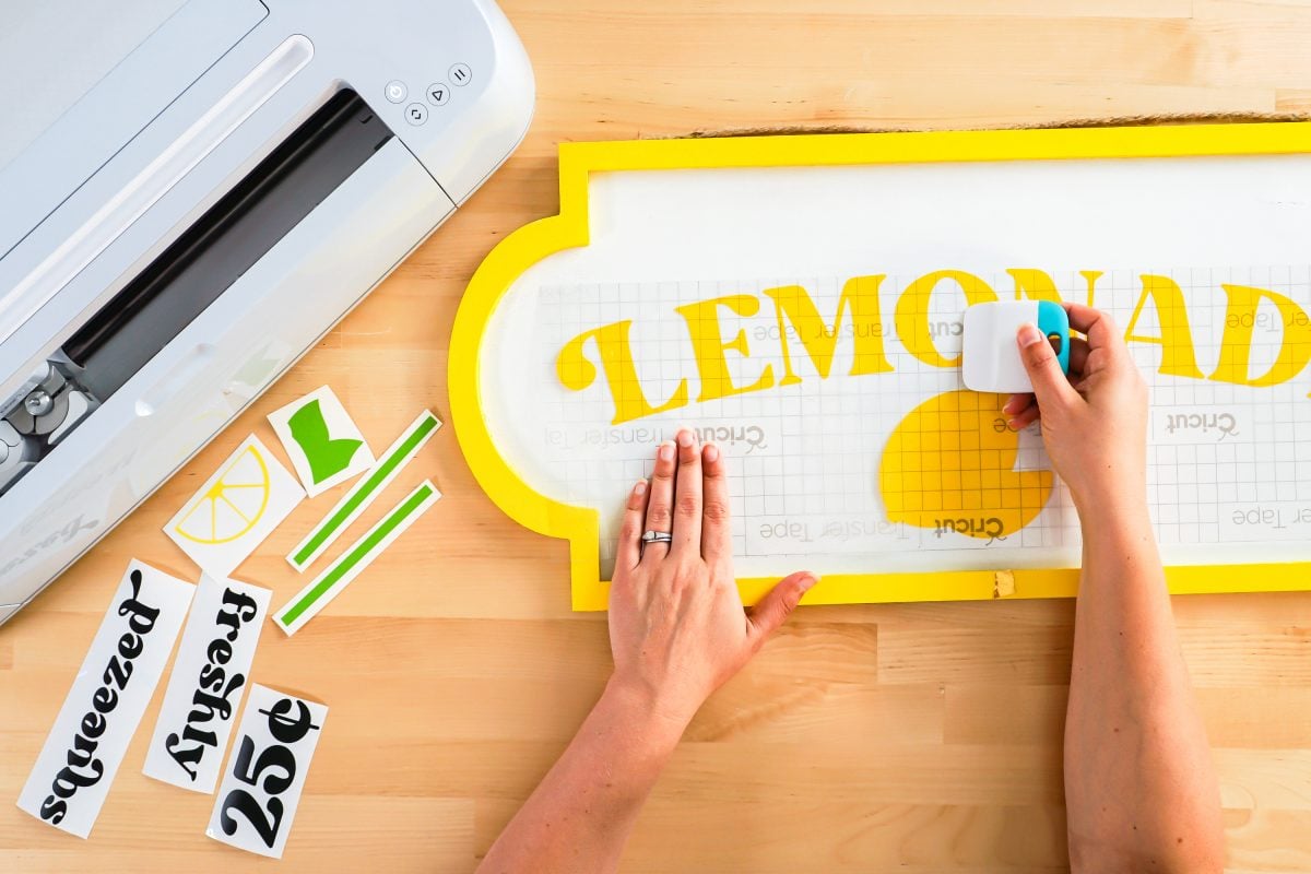 Hands using scraper to burnish the decal to the sign.