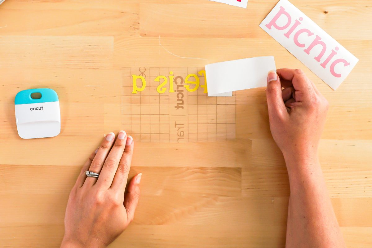 Hand peeling back transfer tape backing.