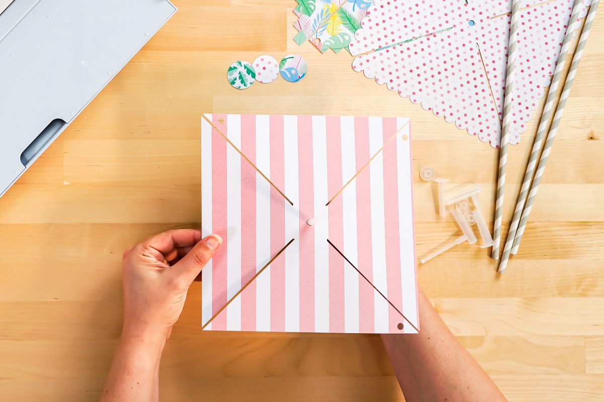 Hands placing paper pinwheel on pinwheel accessory