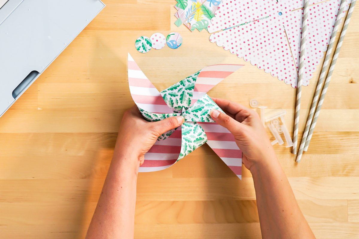 Hands folding pinwheel petals to form pinwheel.