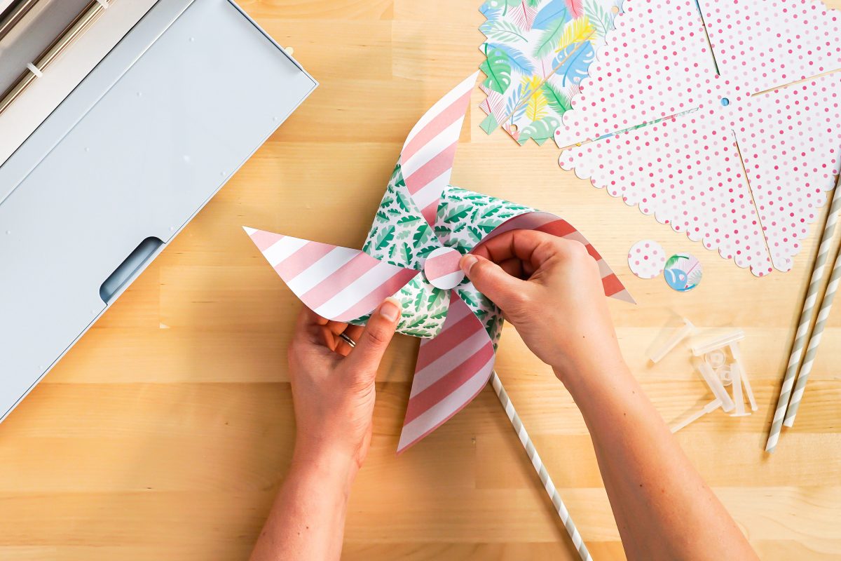 Hands gluing decorative circle onto pinwheel.