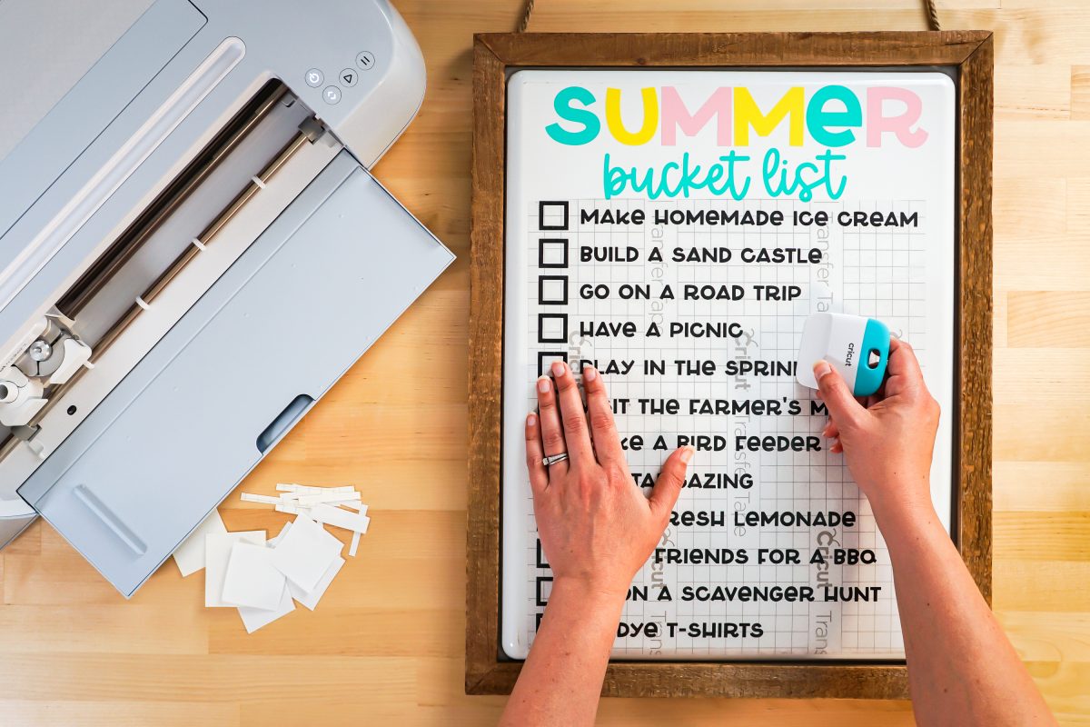 Hands using the scraper to burnish the list to the white board.