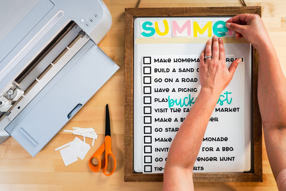 Hands manually adding the word "SUMMER" to the top.