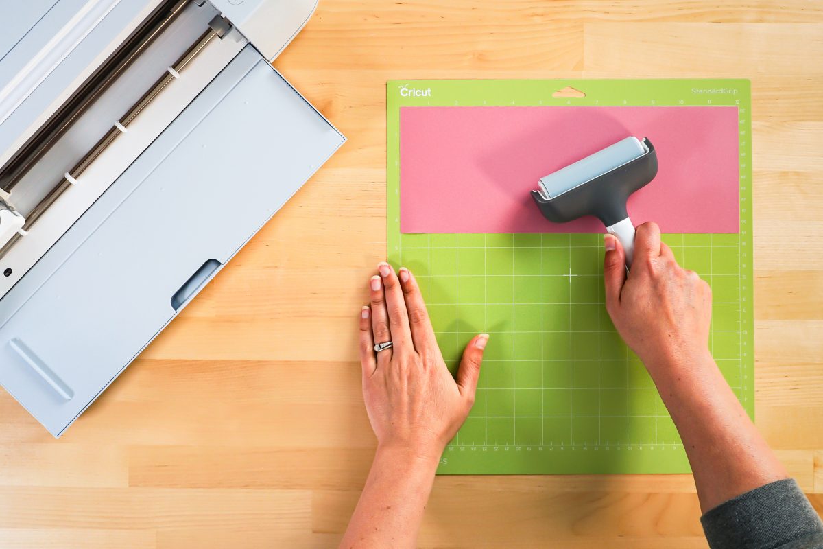 Hand using a brayer to smooth Infusible Ink to mat.