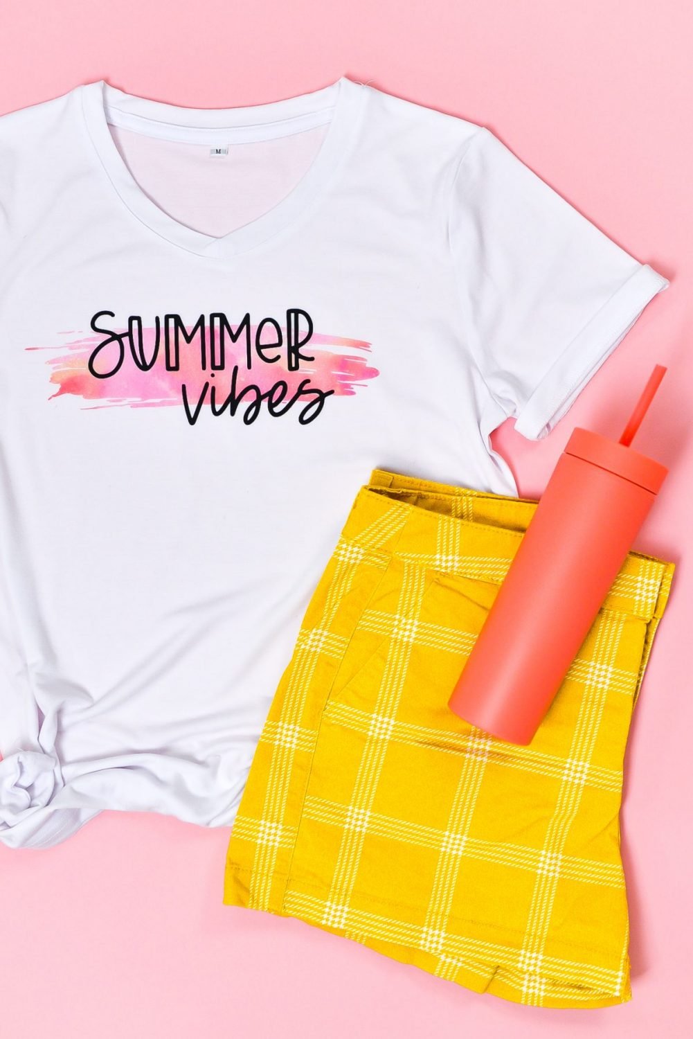 Final Summer Vibes shirt staged with flip flops, water bottle, and shorts on pink background