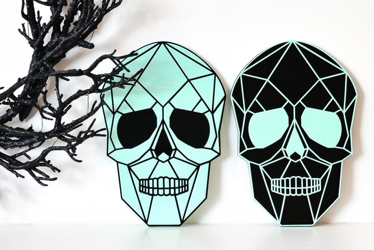 Two skulls on shelf with creepy Halloween wreath.