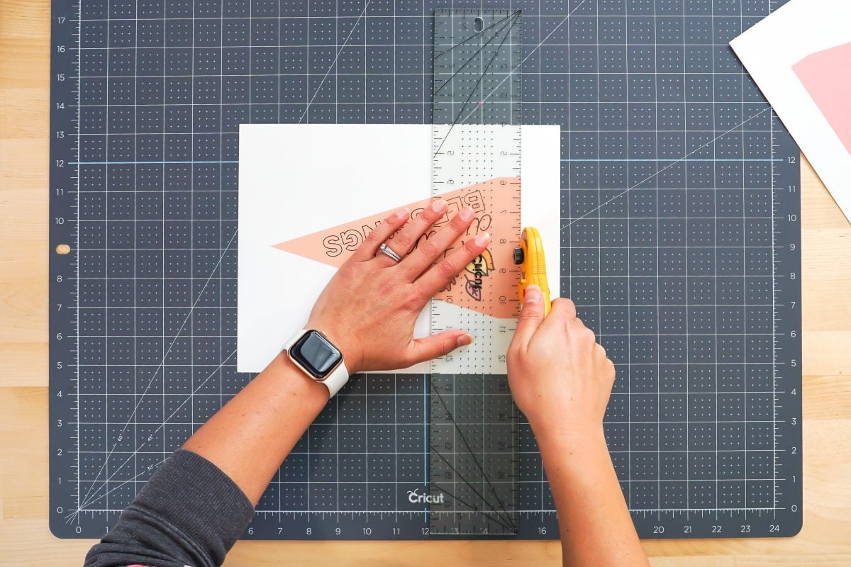 Hands cutting fall pennants using ruler and rotary blade