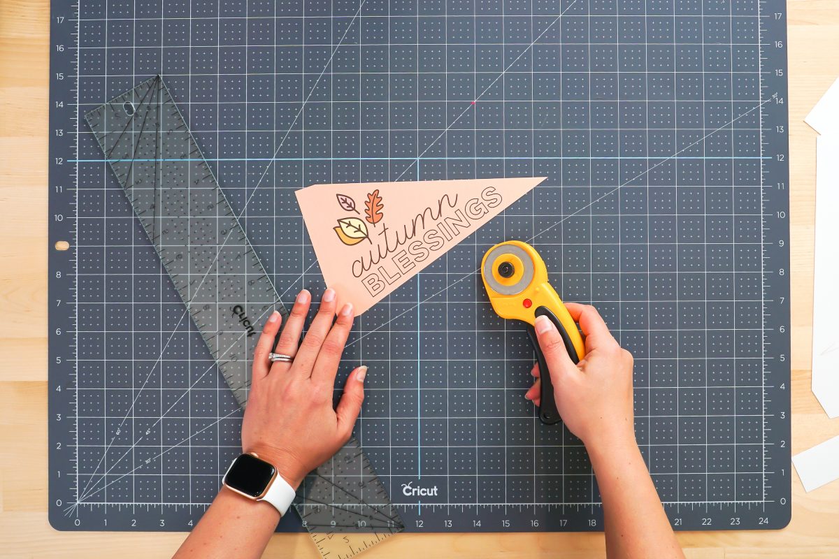 Hands showing cut pennant with rotary blade and ruler.