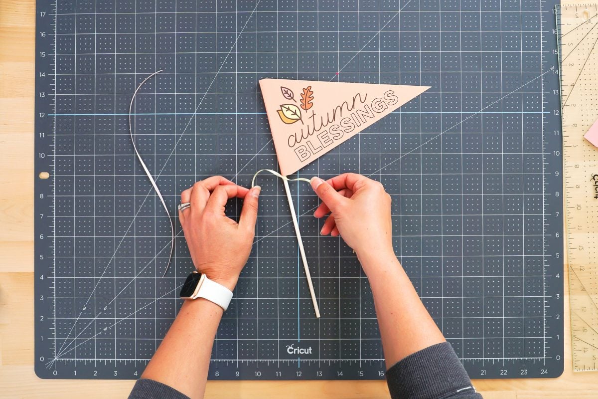 Hands tying ribbon on the dowel below the flag.