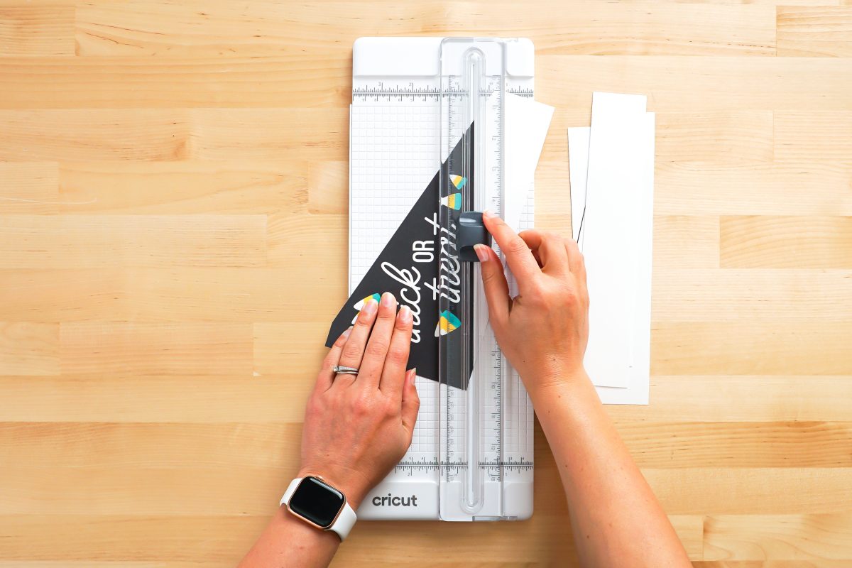 Hands cutting Halloween pennants using paper cutter