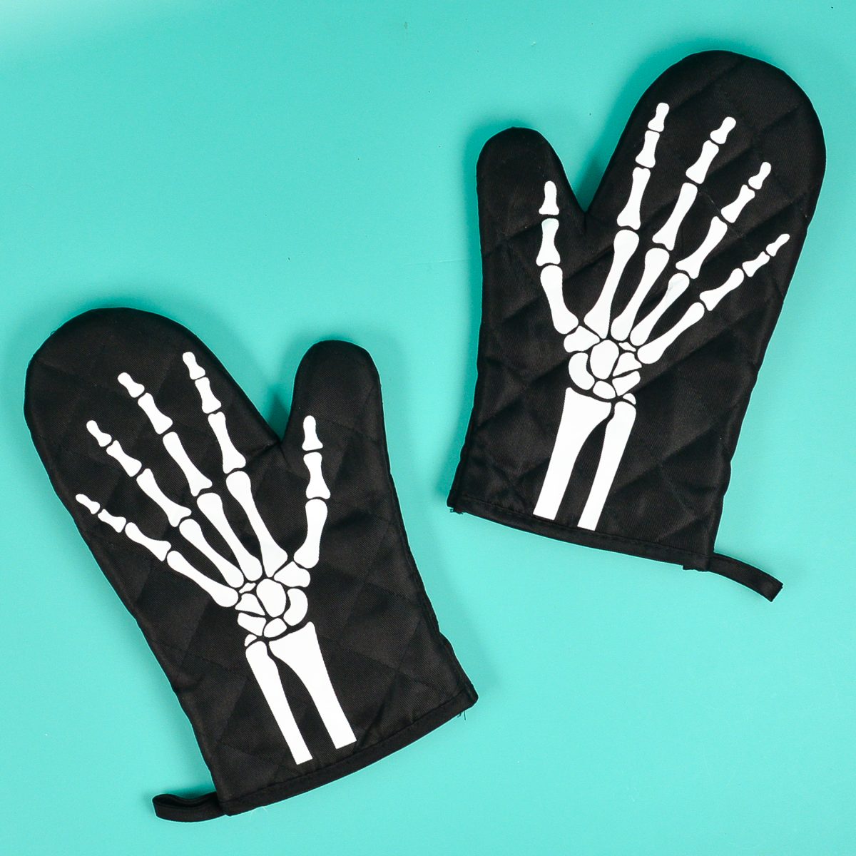 Skeleton oven mitts on teal background.