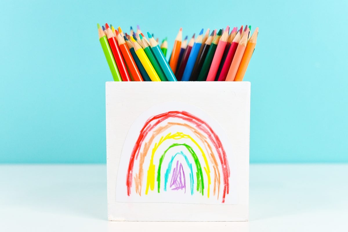 White box with colored pencil rainbow on it, filled with colored pencils.