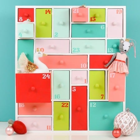 Painted wooden advent calendar staged with a bunch of ornaments