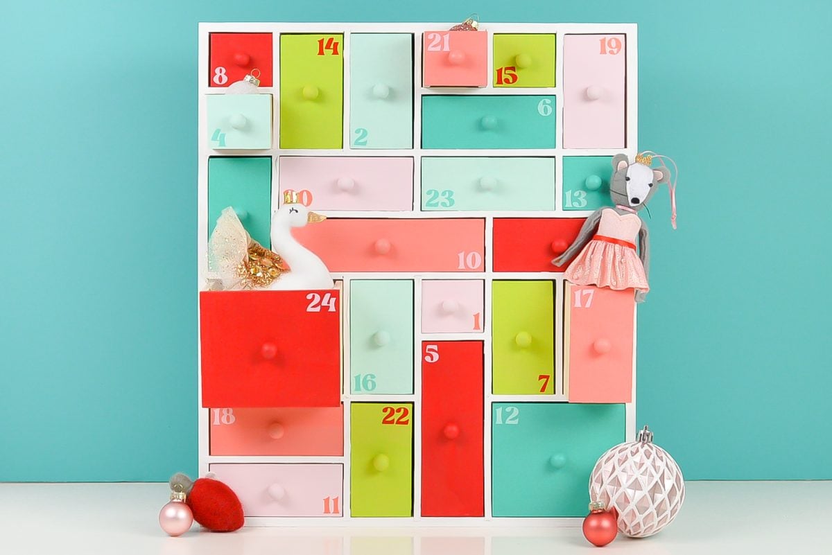 Painted wooden advent calendar staged with a bunch of ornaments