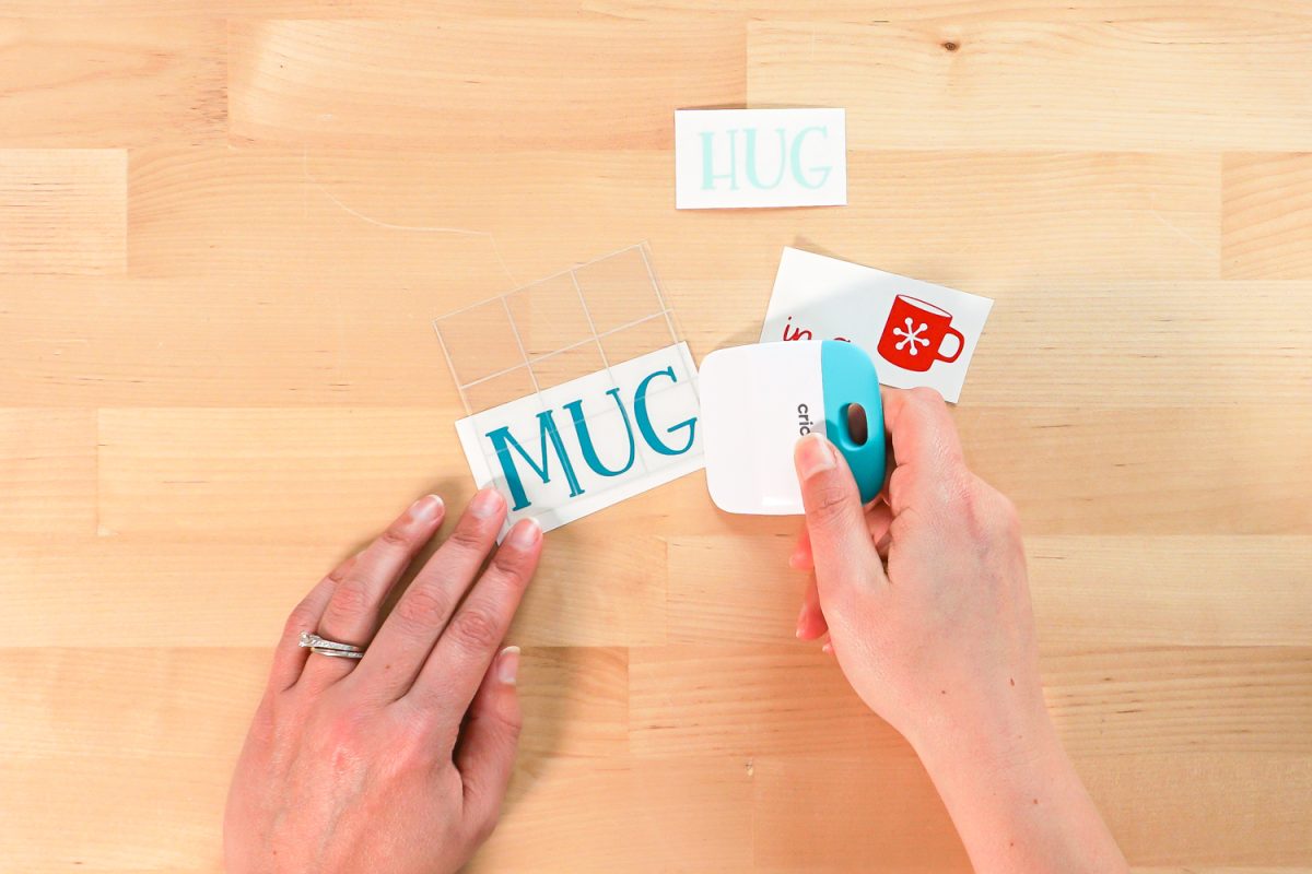 Hands putting transfer tape on weeded HUG image.