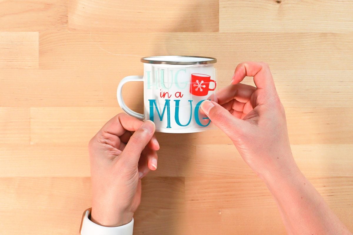 Hands placing decal on mug.