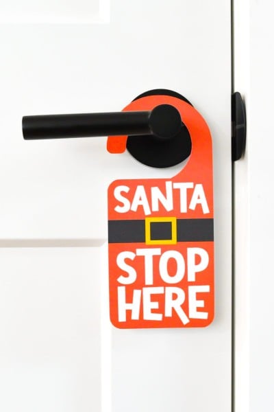 Santa Stop Here door hanger on white door with black knob