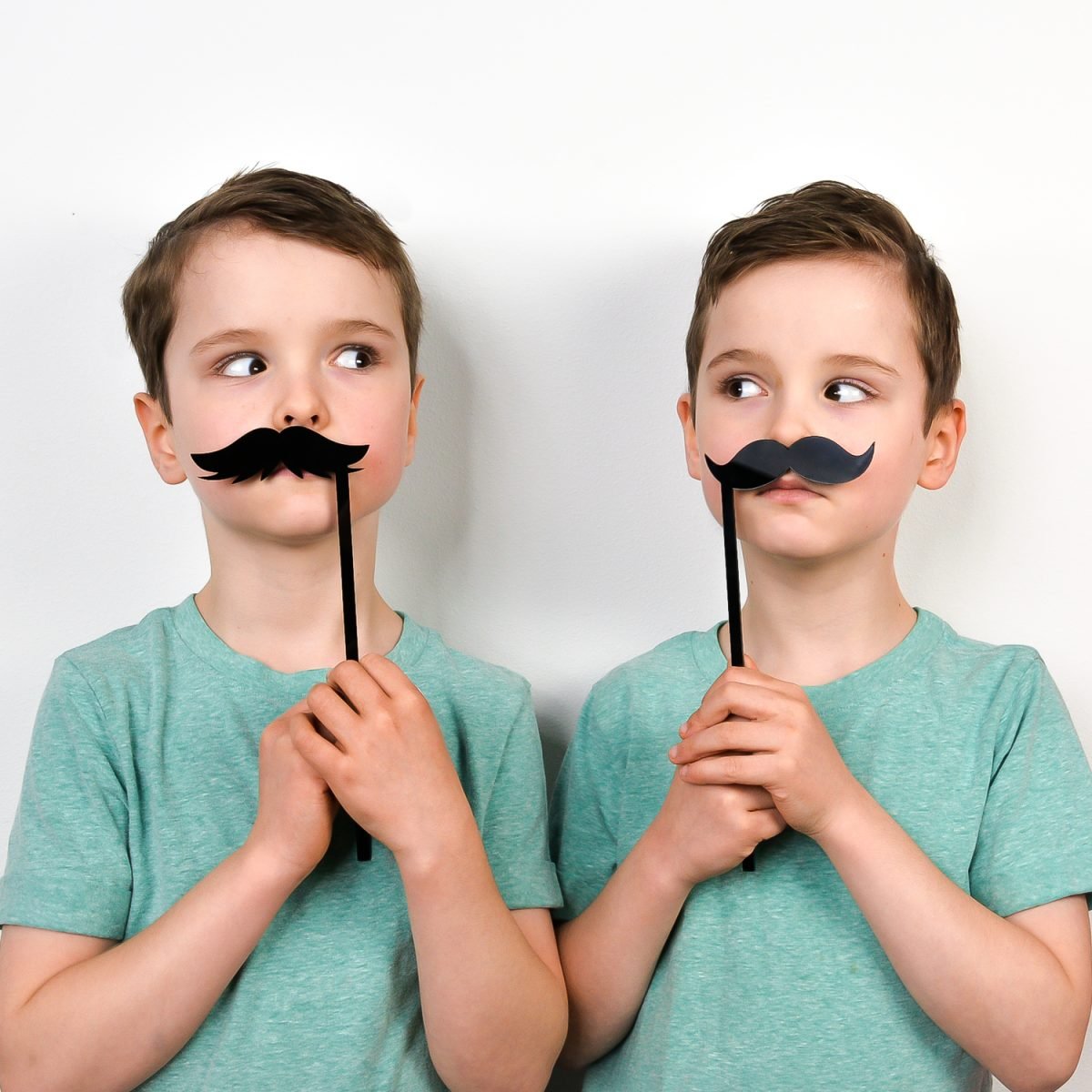 Twin boys using mustache DIY photo booth props