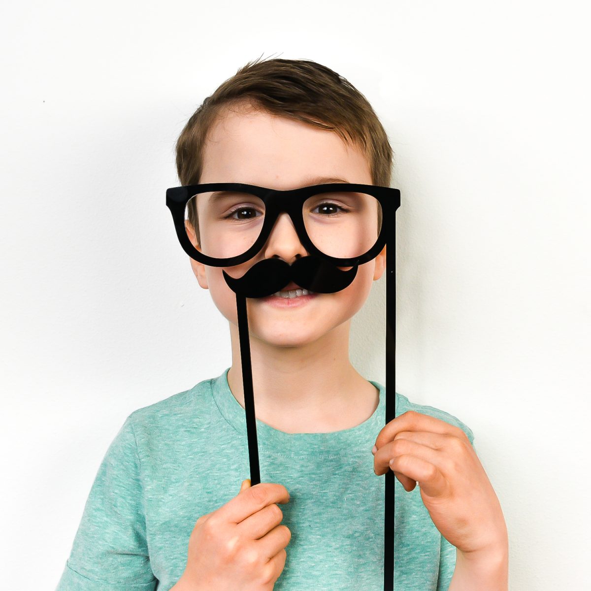 Boy holding mustache and glasses photo props