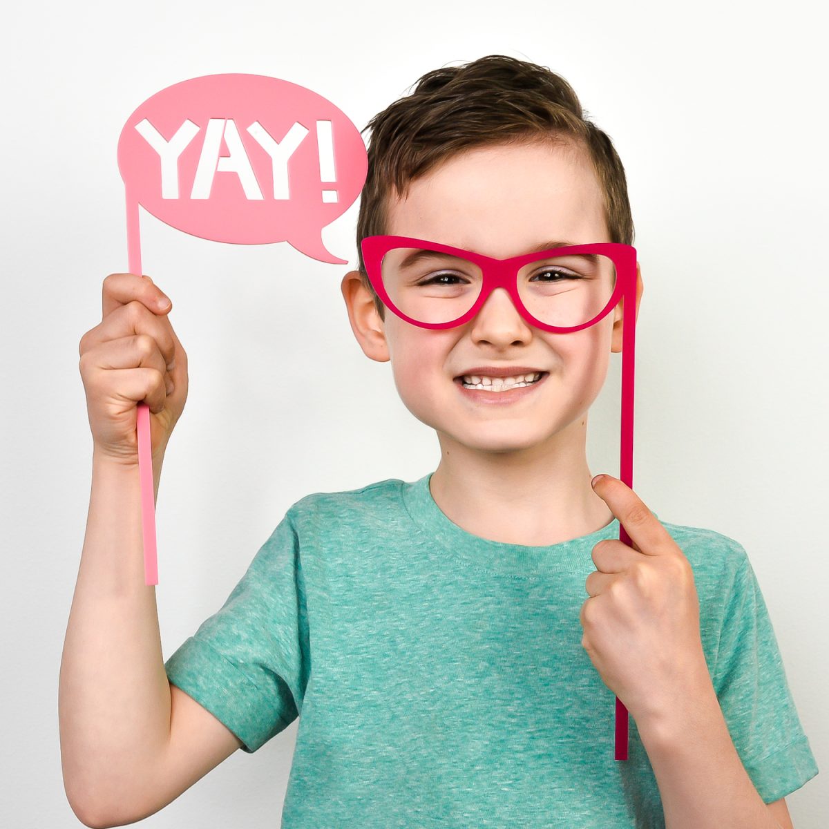 Boy holding glasses and YAY photo booth props.