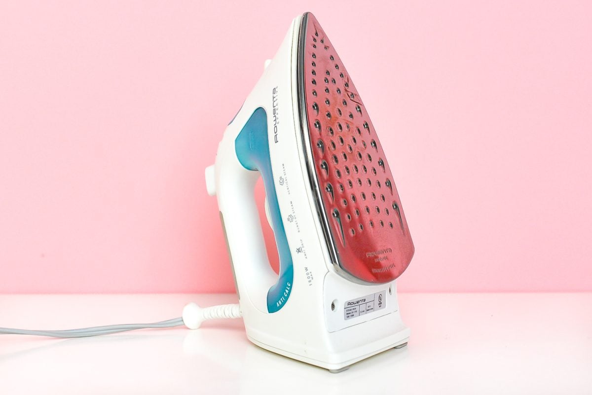 Household iron on pink background