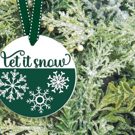 Round Christmas ornament decorated with snowflakes and the words Let it Snow