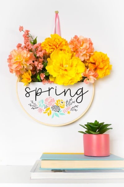Spring embroidery hoop wreath staged with framed photo and books.