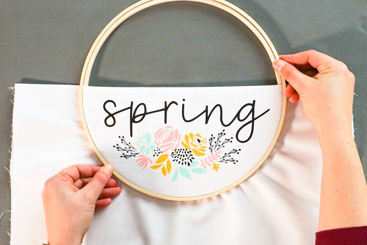 Hands placing fabric between the two pieces of the embroidery hoop.