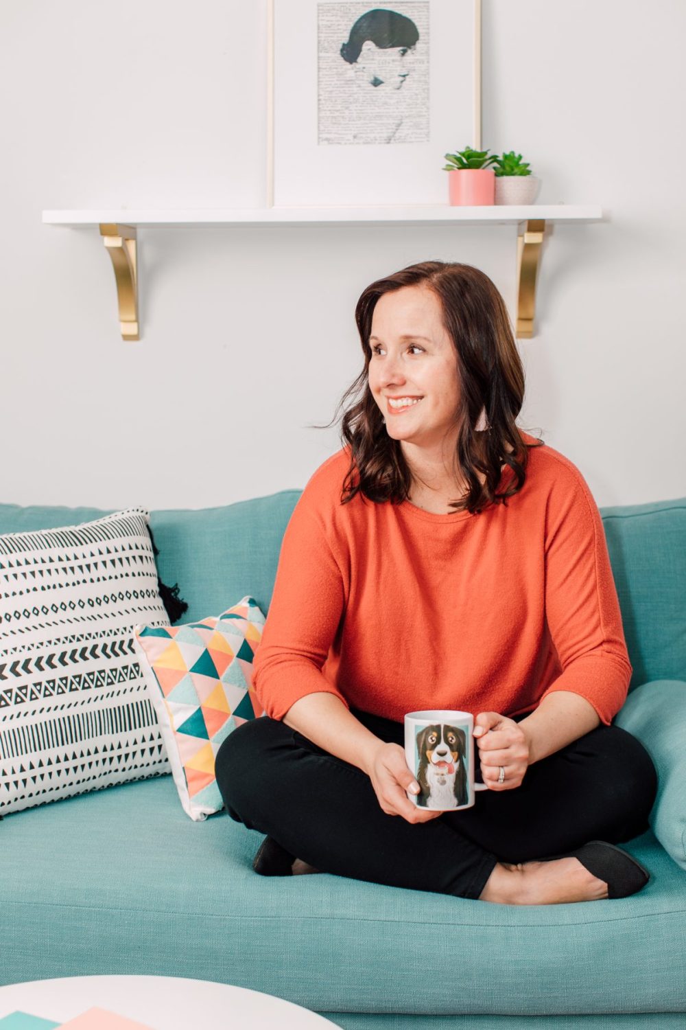 Cori of HLMS sitting on couch in her craft room holding a coffee mug