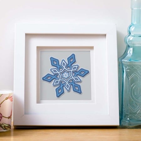 Snowflake layered art in a white shadow box frame
