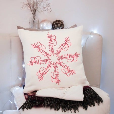 White pillow with a red Silent Night snowflake SVG on it
