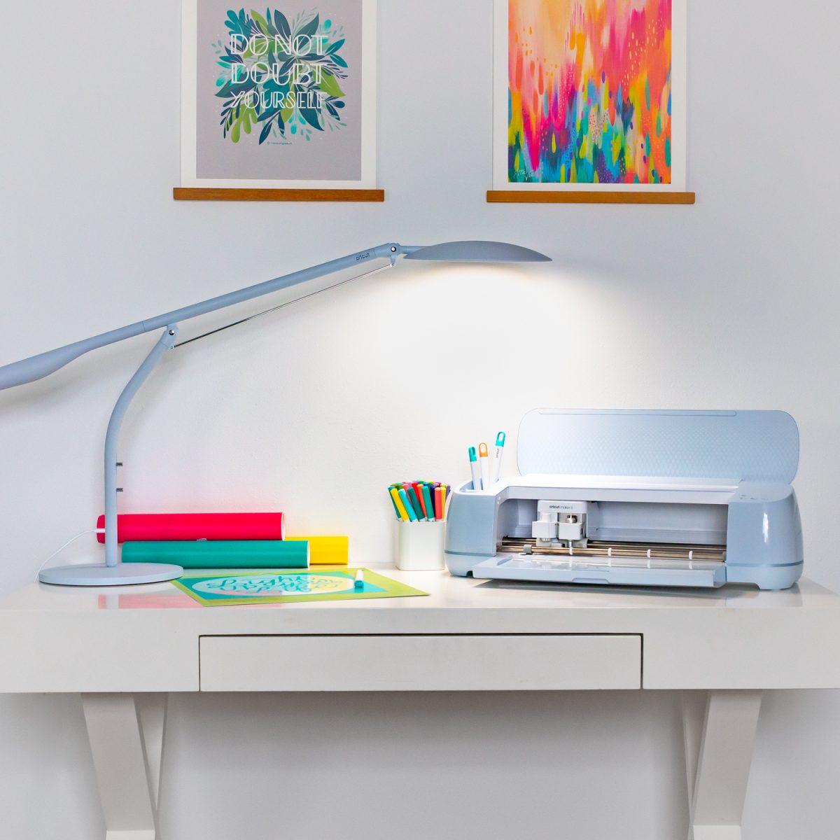 Cricut Bright 360 Desk Model next to desk with Cricut Maker 3 and Cricut projects