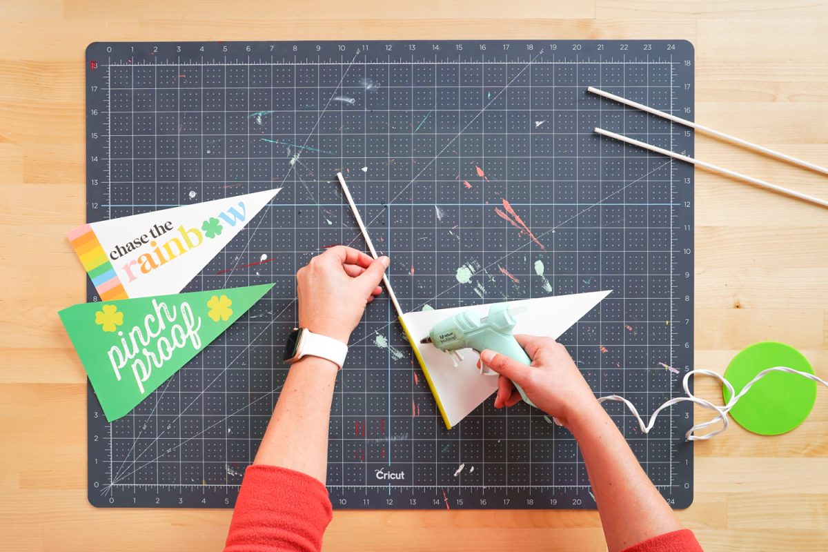 gluing pennant to dowel rod using hot glue gun