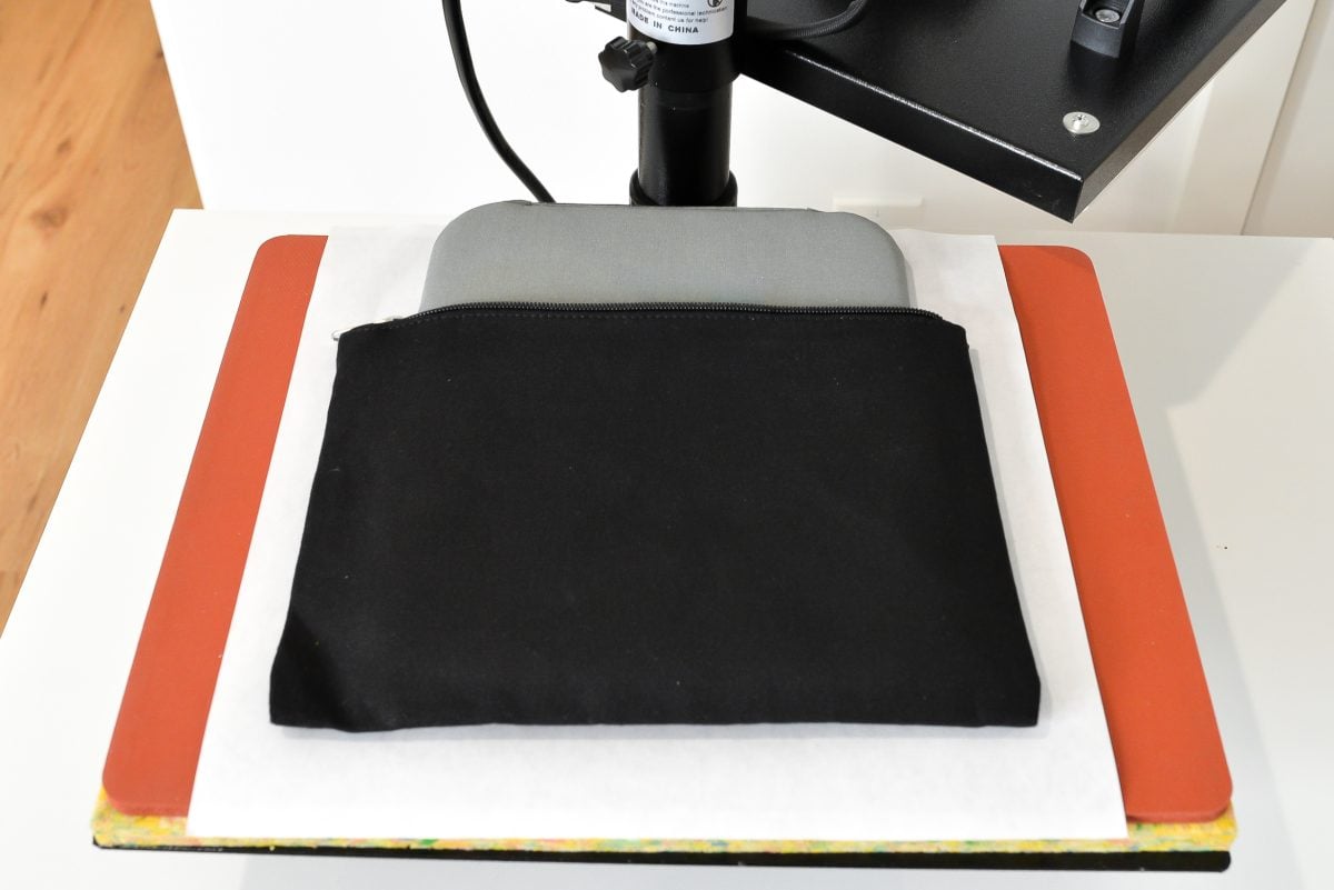 Black zippered pouch on heat press base with EasyPress mat inside.