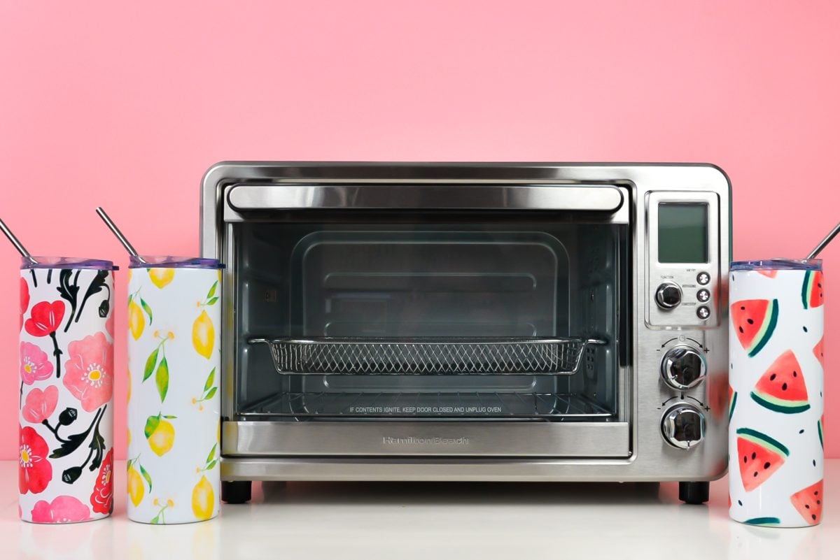 Sublimated tumblers with convection oven with pink background.