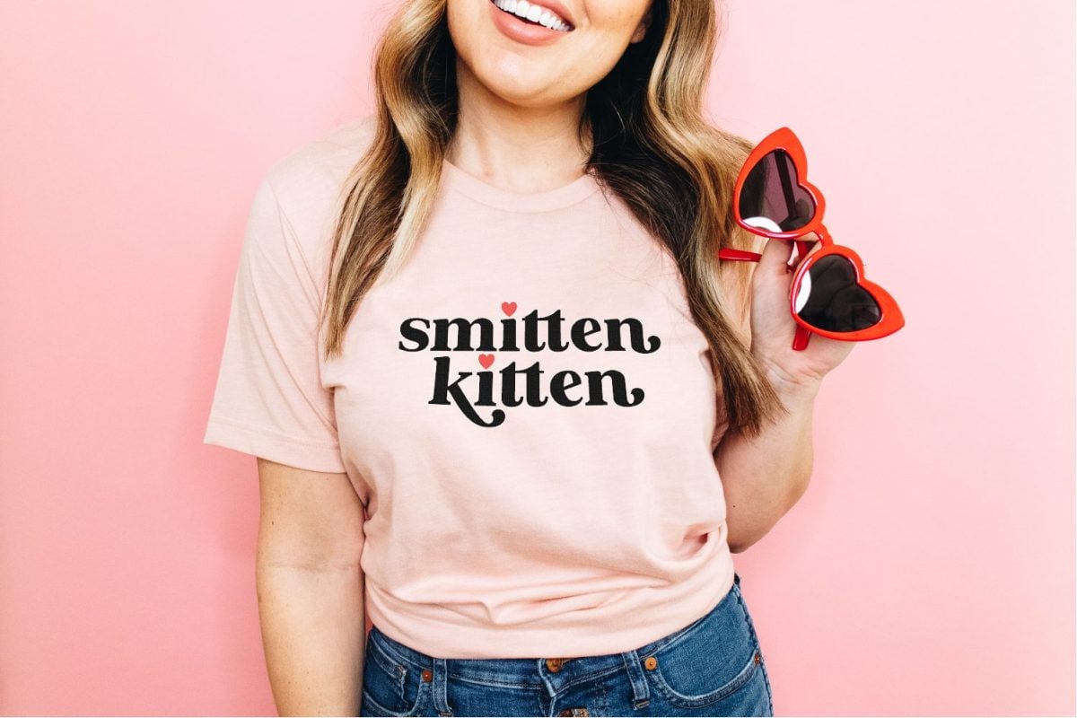 Woman wearing a pink t-shirt that says Smitten Kitten on it