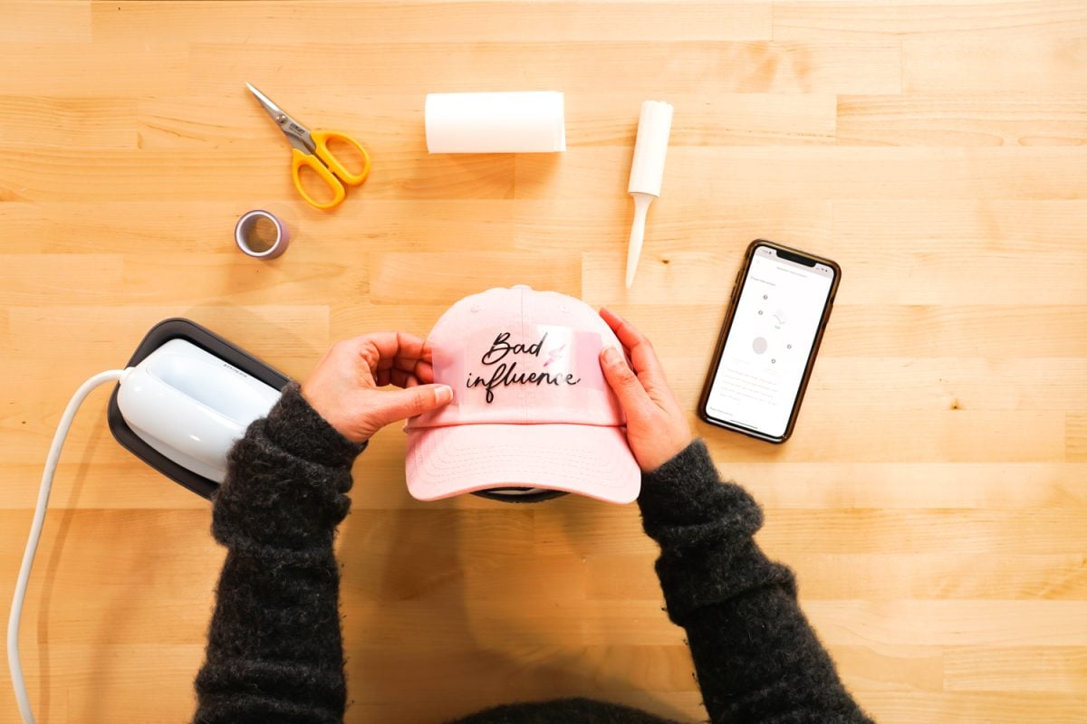 Hands adhering decal to a pink hat