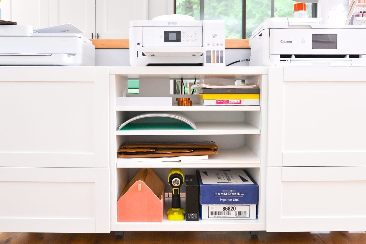 Craft room tour: Media console with three printers and supplies on shelves. 